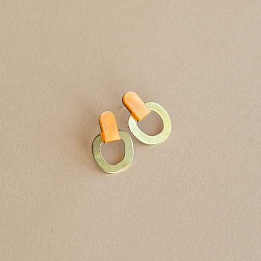 Orange brass stud earrings handmade in the UK from FSC wood, recycled brass and acrylic with nickel-free posts on light beige background.