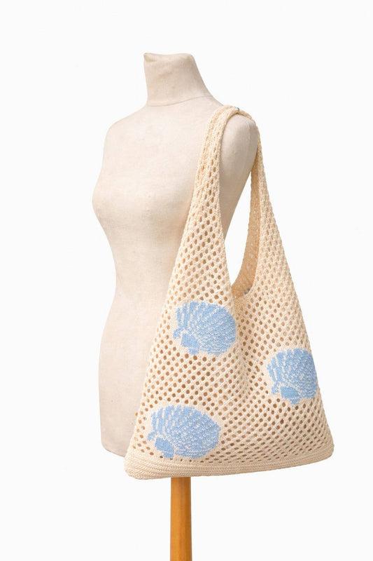 Beige mesh bag with blue floral patterns on a mannequin against a white background