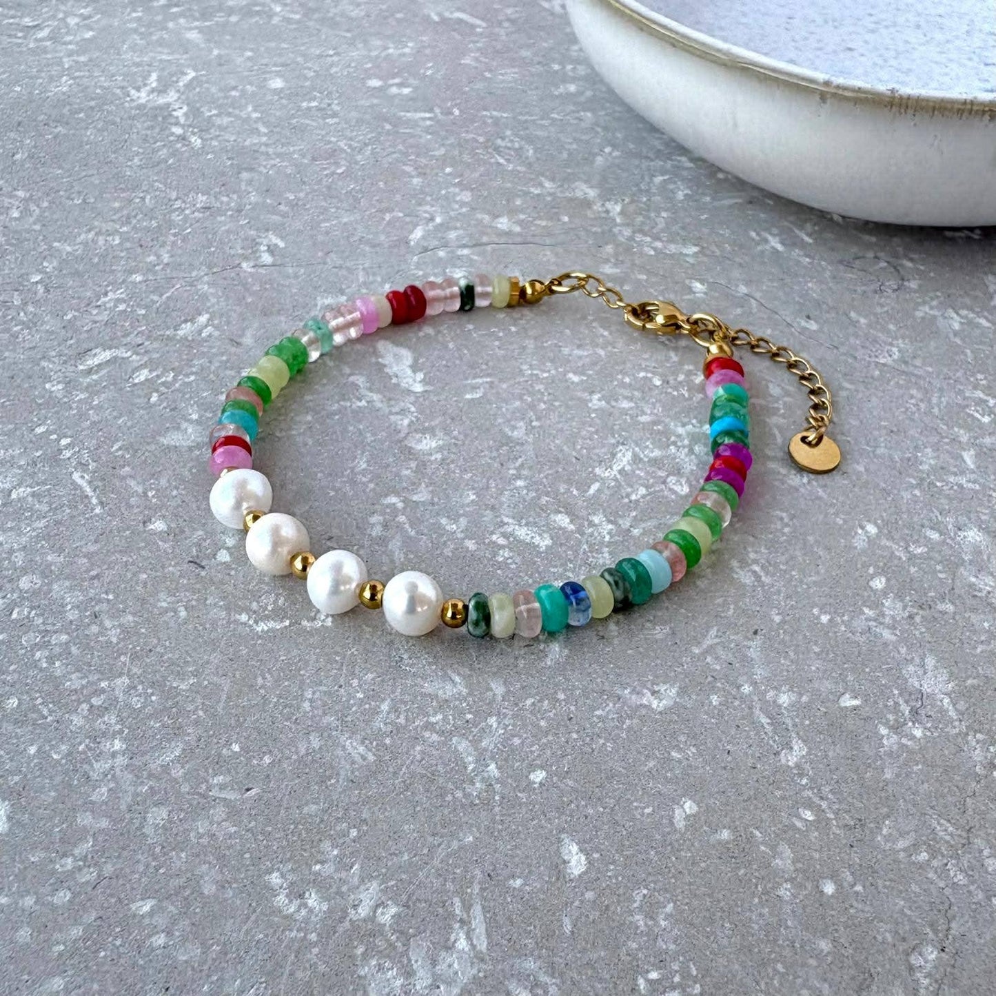 Multicolored beaded bracelet with gold accents on a gray surface