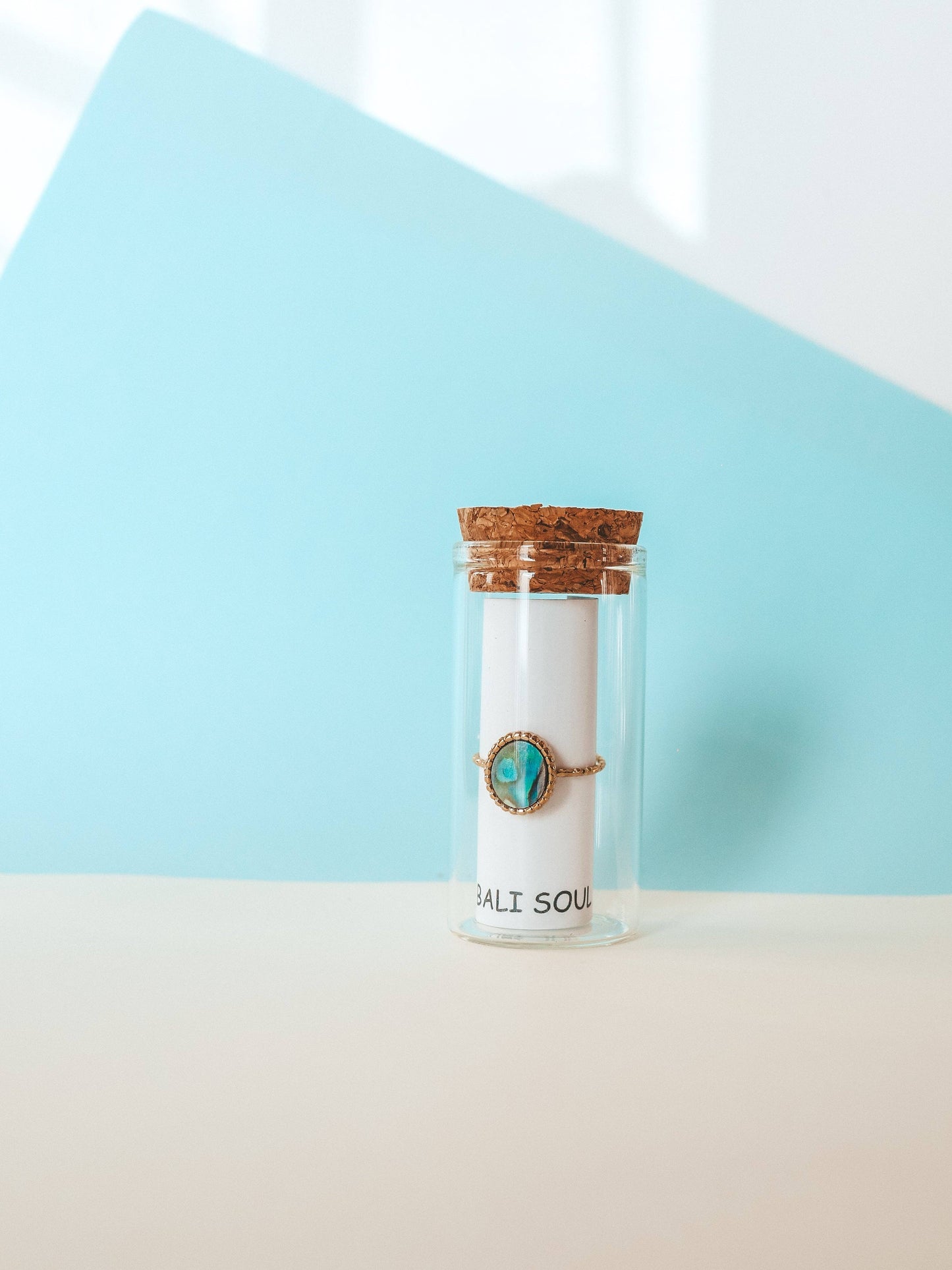Jar with a candle and turquoise stone on a light blue and beige background