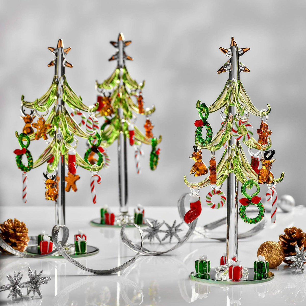 Decorative Christmas trees with ornaments on a reflective surface