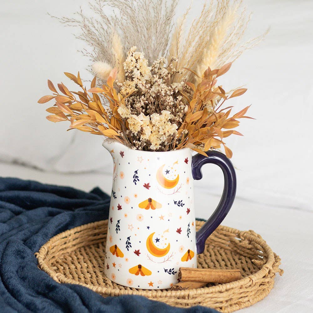 Decorative pitcher with dried flowers on a woven mat