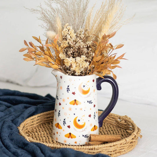 Decorative pitcher with dried flowers on a woven mat