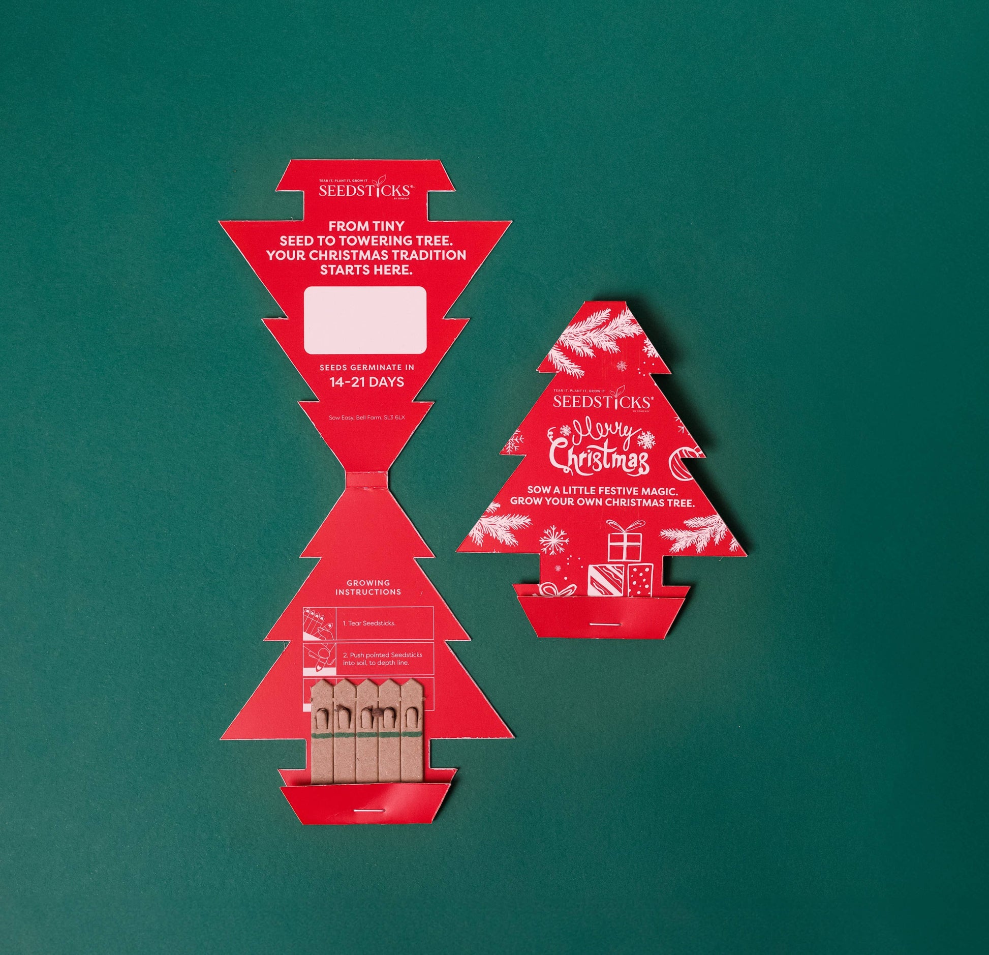 Red Christmas tree-shaped packaging with wooden seed sticks on a green background