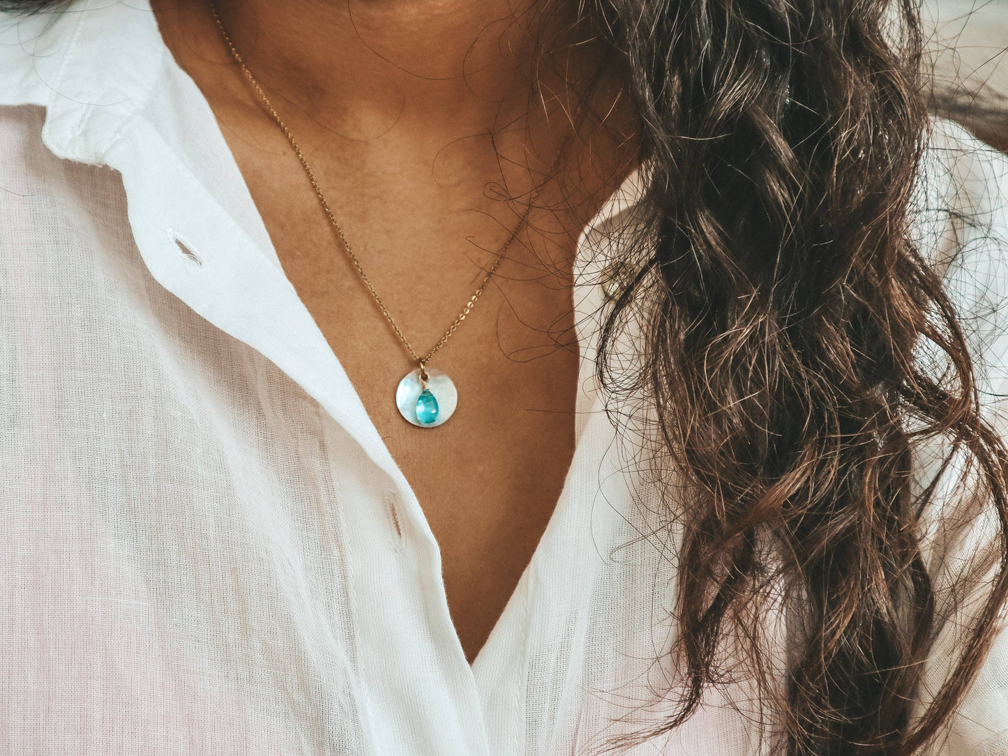 Necklace with a pendant worn by a person in a white shirt