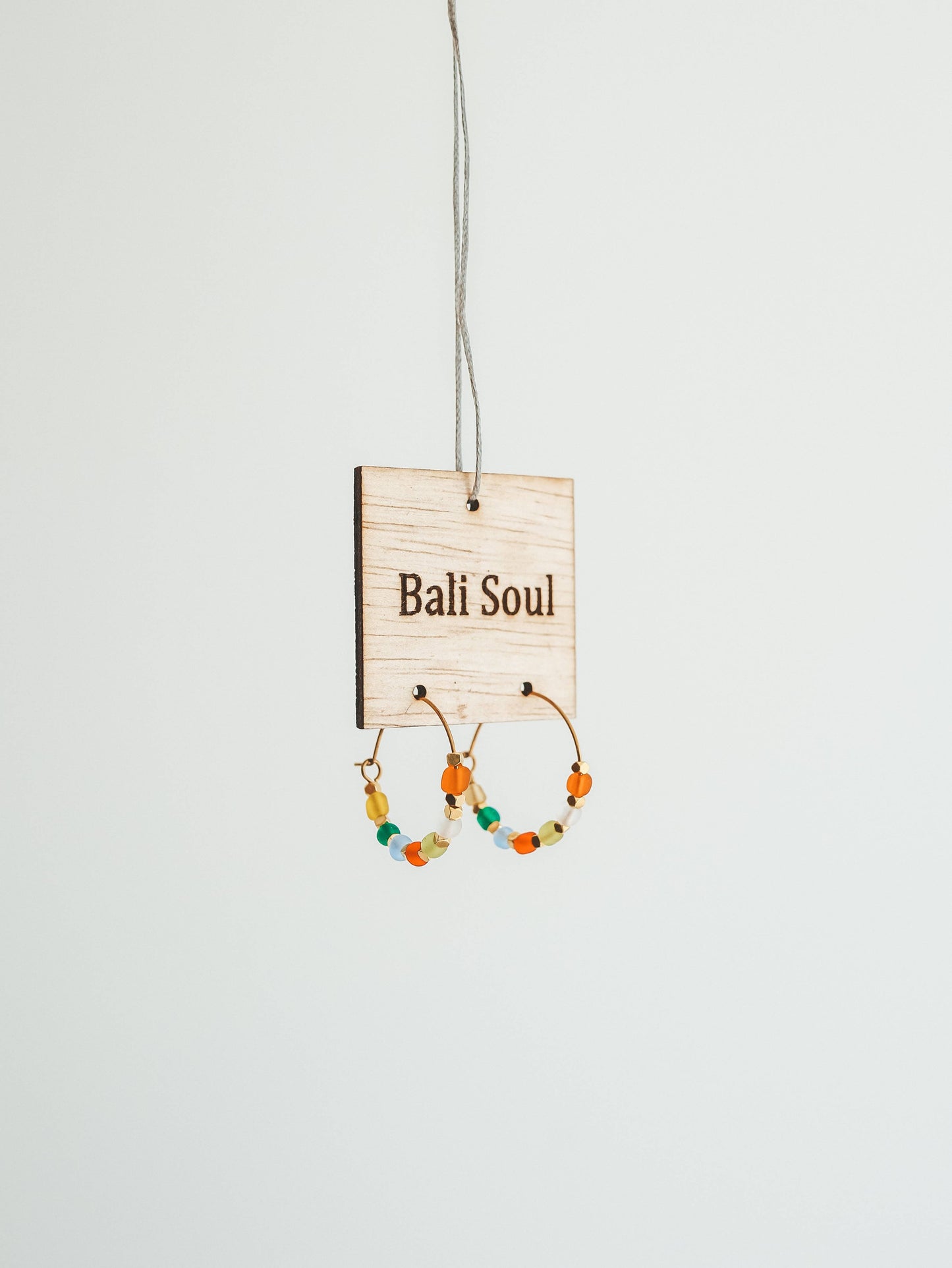 Earrings hanging on a 'Bali Soul' branded card against a white background