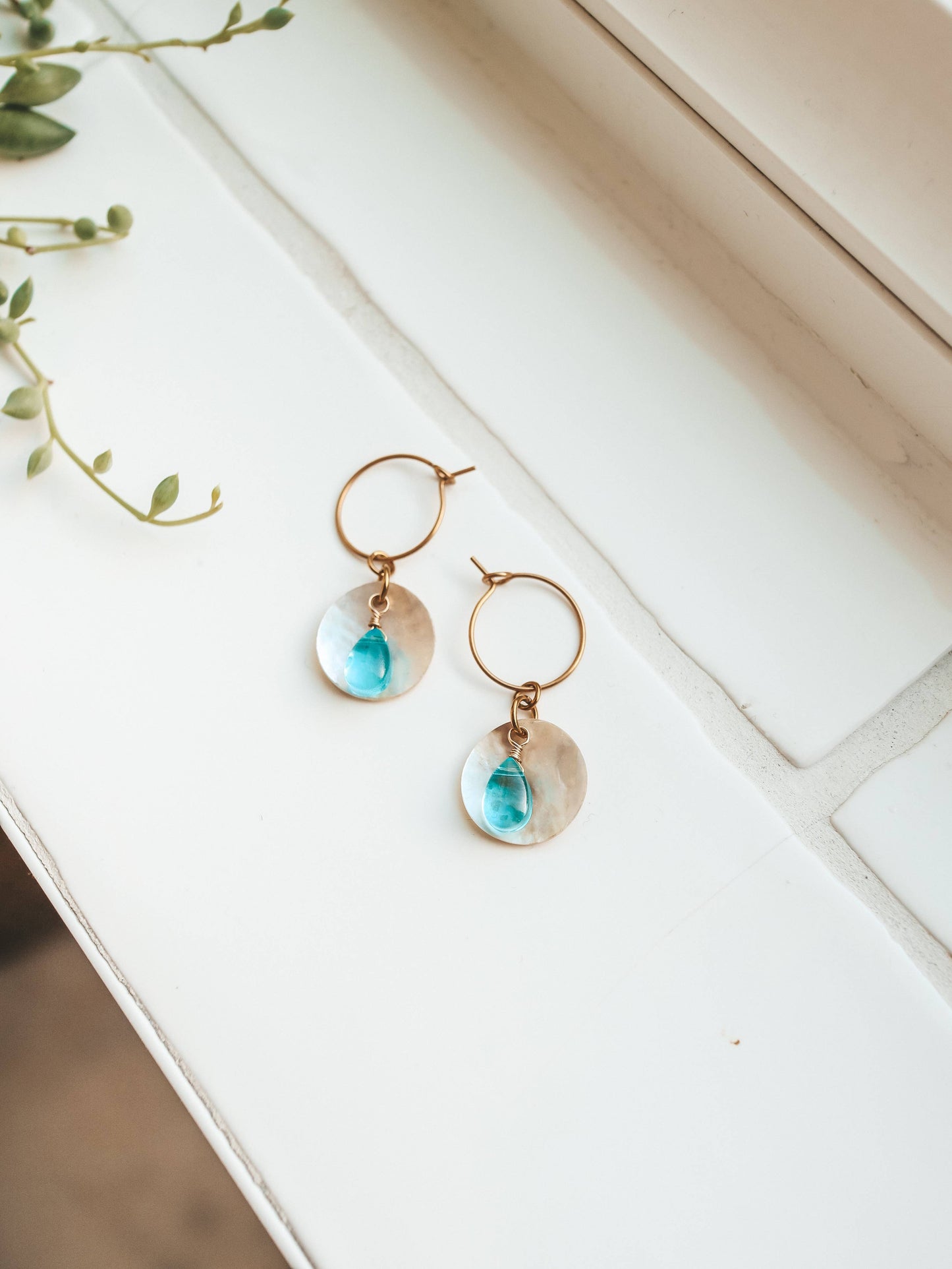 Gold earrings with turquoise drops on a white surface