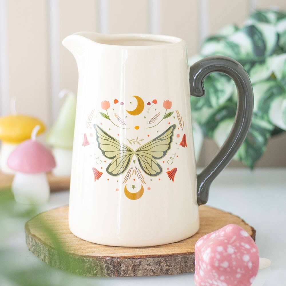 White ceramic pitcher with butterfly design on a wooden coaster