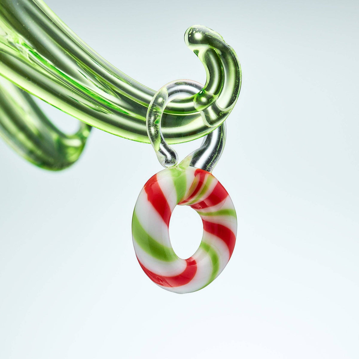 Glass pipe with a candy cane-shaped piece on a light gray background