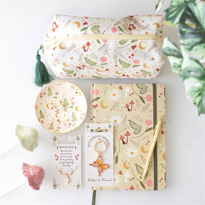 Floral-themed stationery items including a pouch, notebook, and jewelry on a white surface.