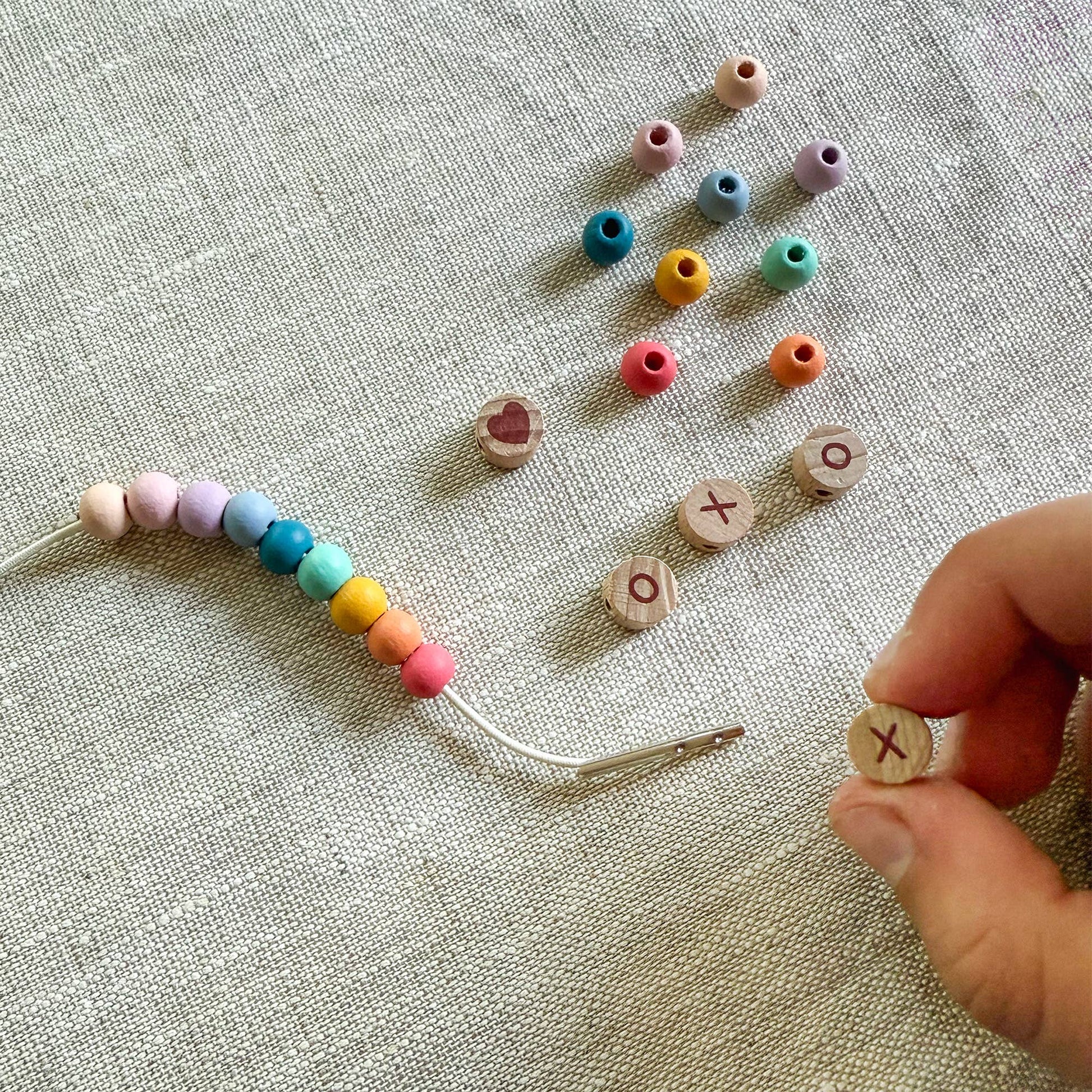 Colorful beaded string with letter beads on a textured fabric background