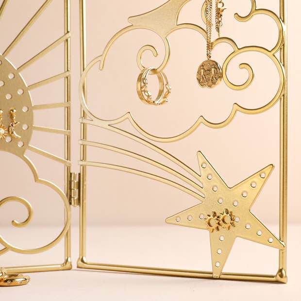 Gold jewelry display with rings and a necklace on a decorative stand.