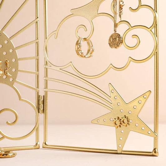 Gold jewelry display with rings and a necklace on a decorative stand.