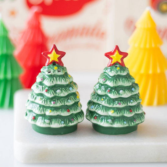 Two Christmas tree-shaped candles with star toppers on a white surface.