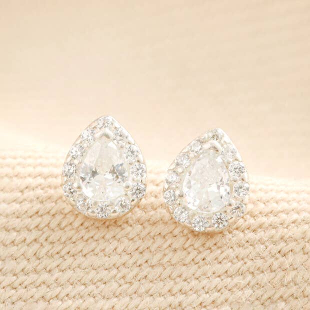 Crystal teardrop stud earrings shown on beige mesh