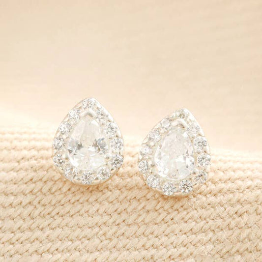 Crystal teardrop stud earrings shown on beige mesh