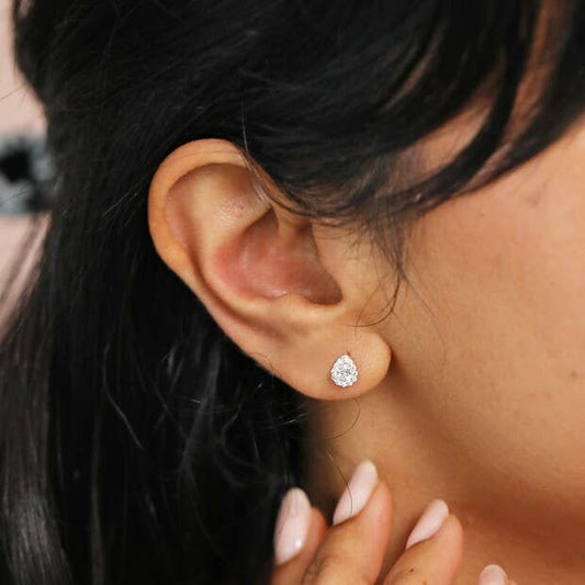 Close-up of an ear wearing a diamond earring with a blurred background
