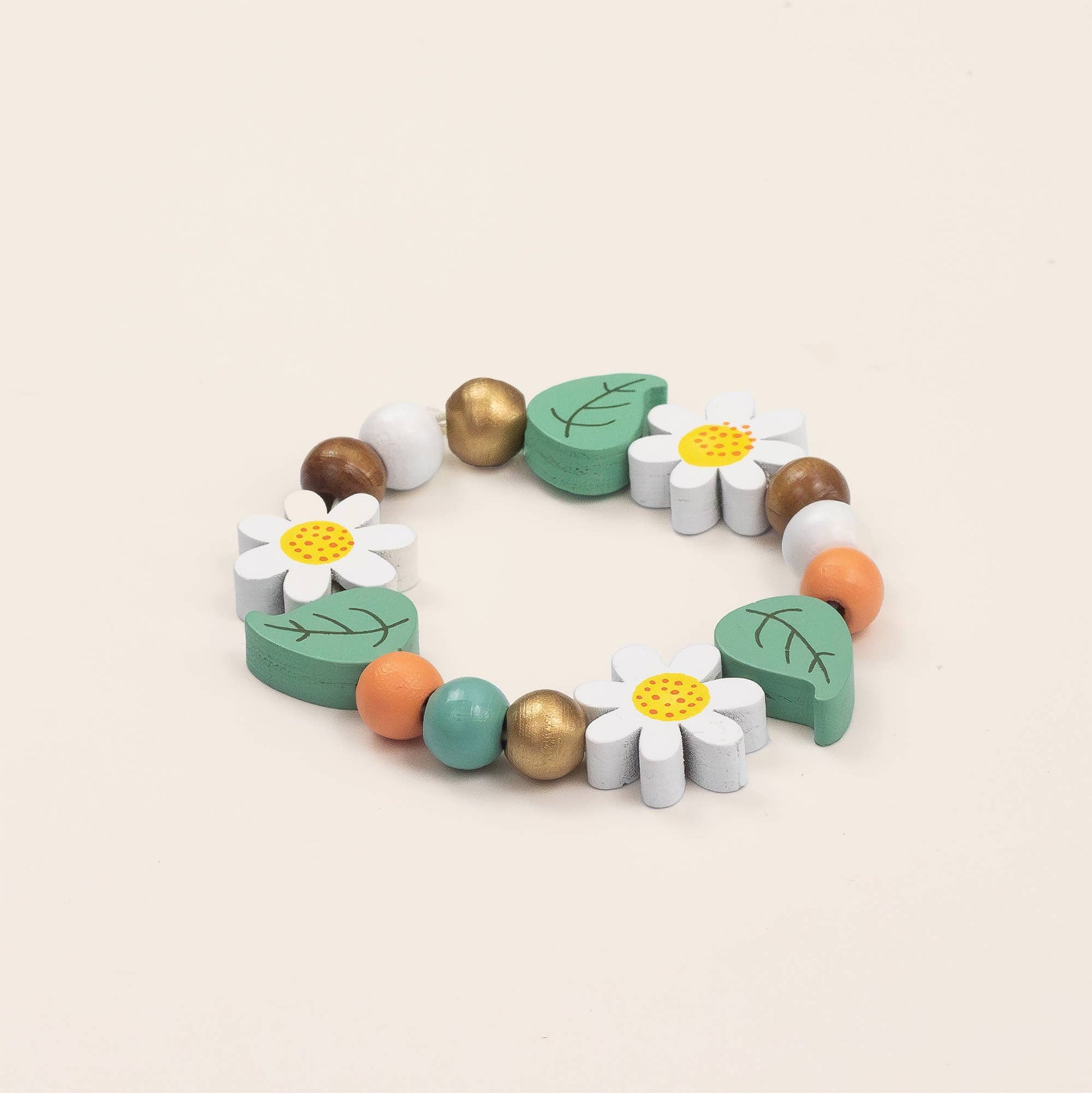 Colorful wooden bracelet with flowers and leaves on a beige background