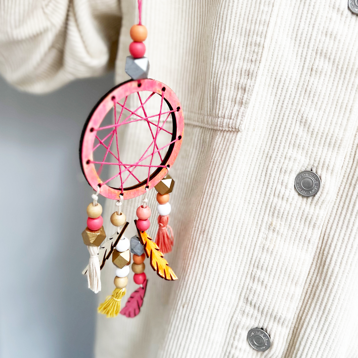 Colorful dreamcatcher hanging on a light-colored fabric background