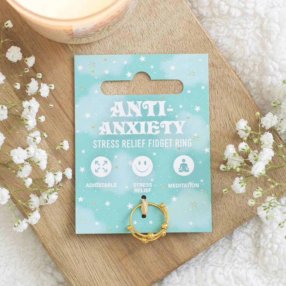 Anti-anxiety stress relief fidget ring packaging on a wooden board with flowers.
