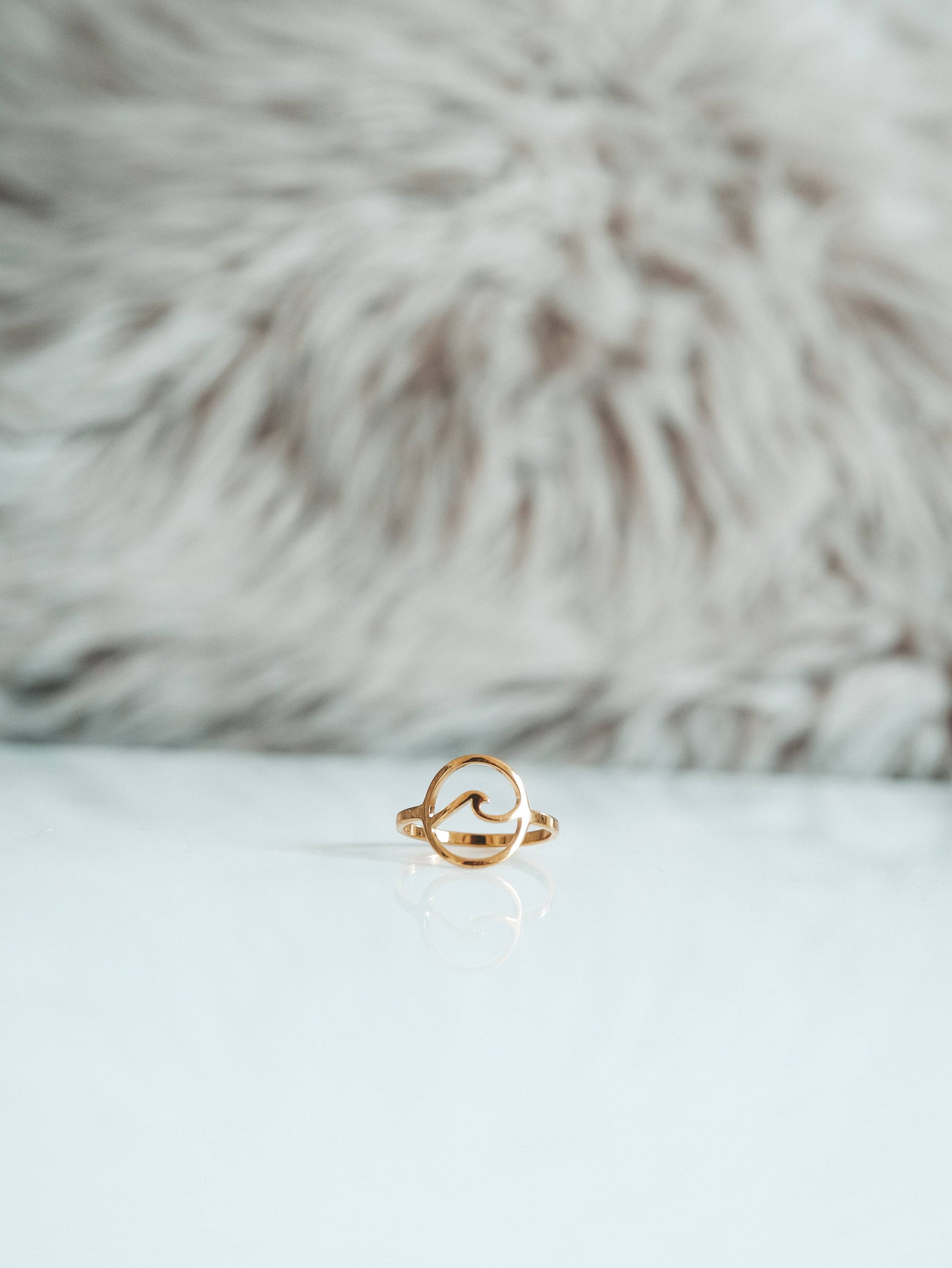 Gold ring on a white surface with a fur background