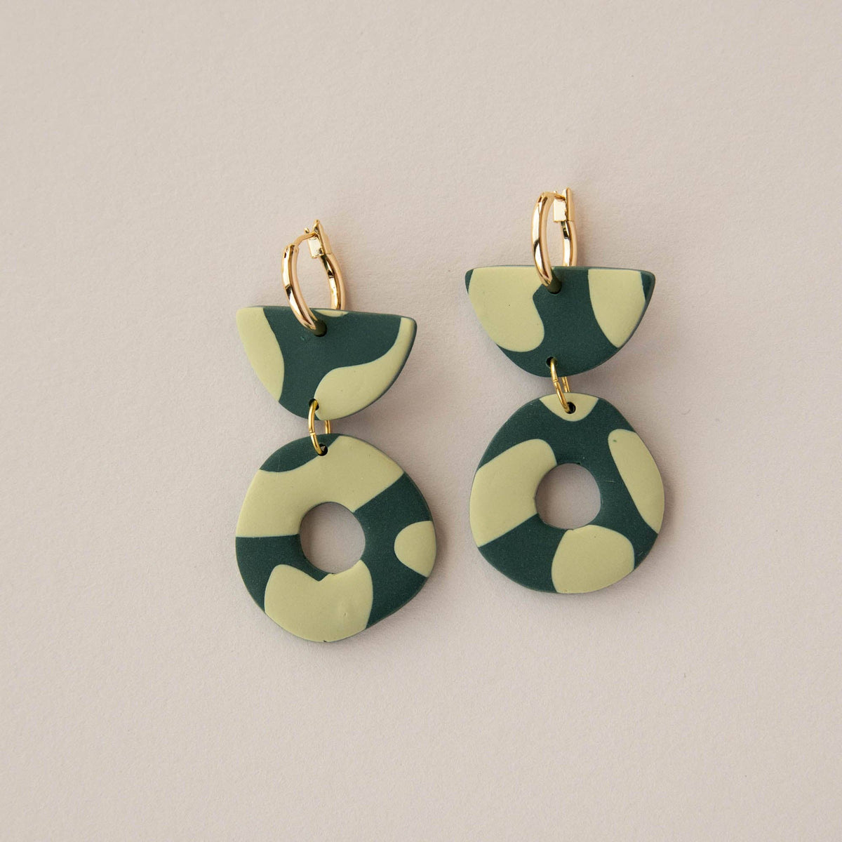 Green and beige patterned earrings on a beige background