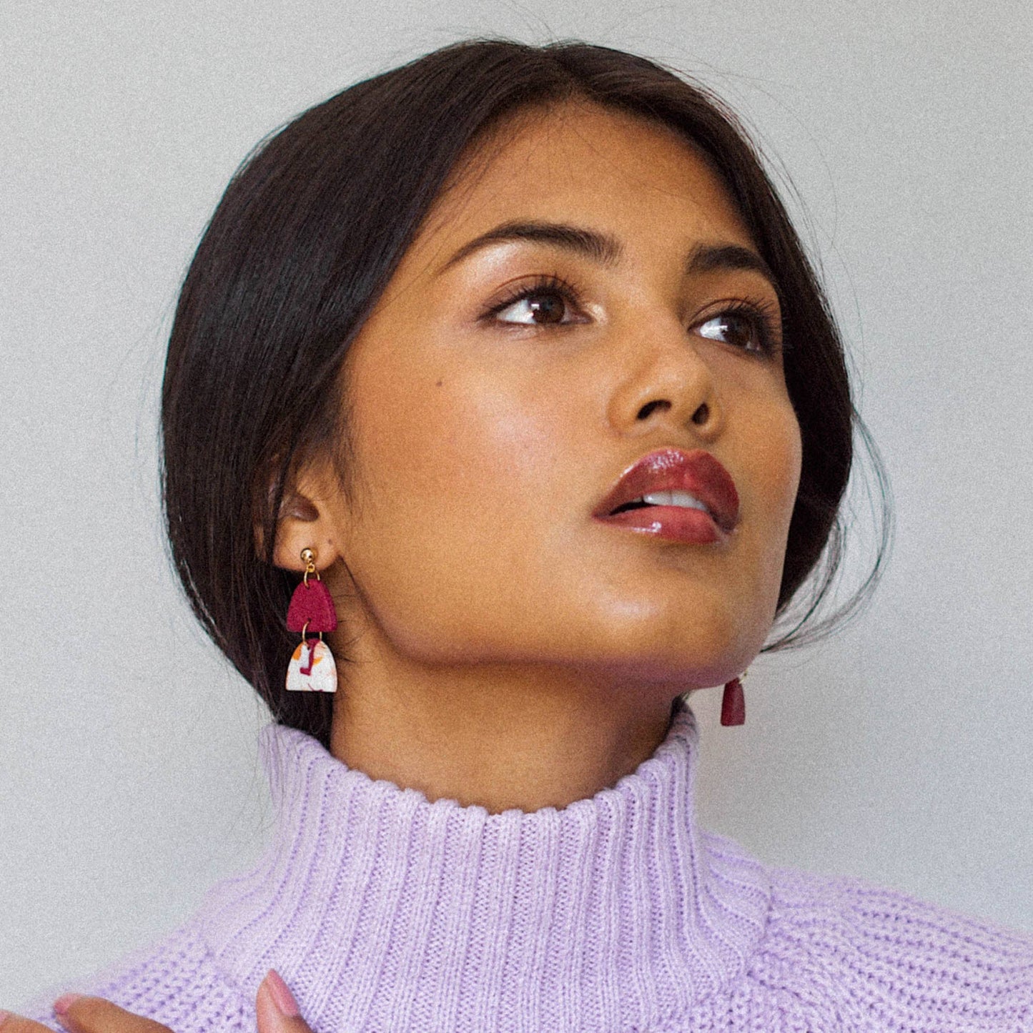 Woman wearing Handmade polymer clay earrings in berry pumpkin and peach earrings with a light gray background