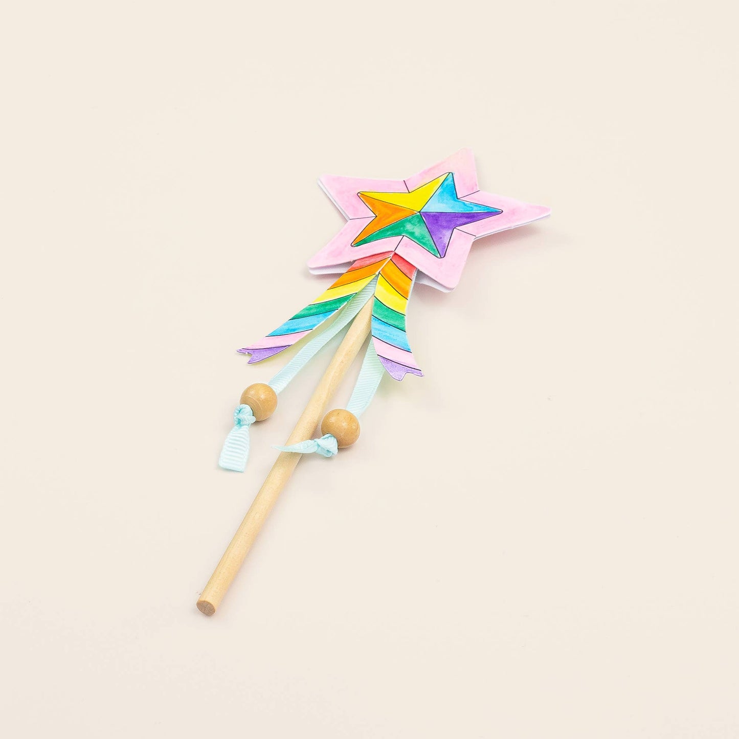 Colorful star-shaped wand with a rainbow design on a beige background