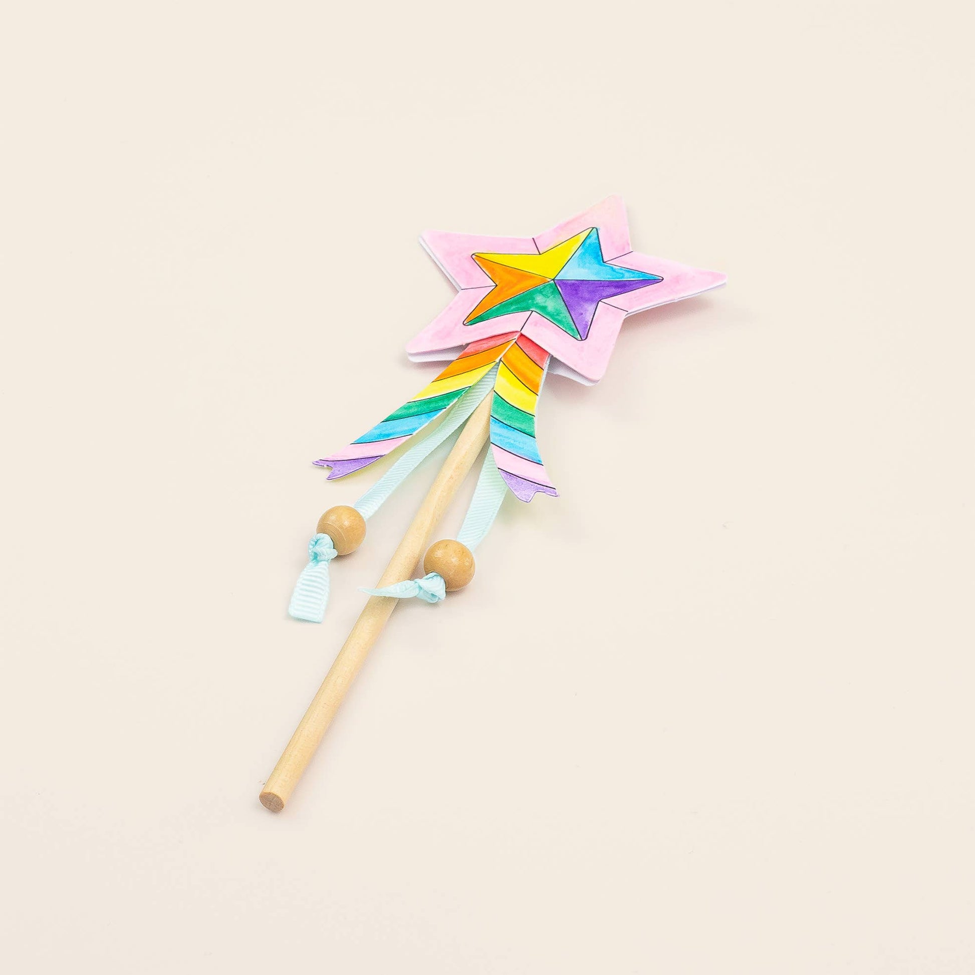 Colorful star-shaped wand with a rainbow design on a beige background