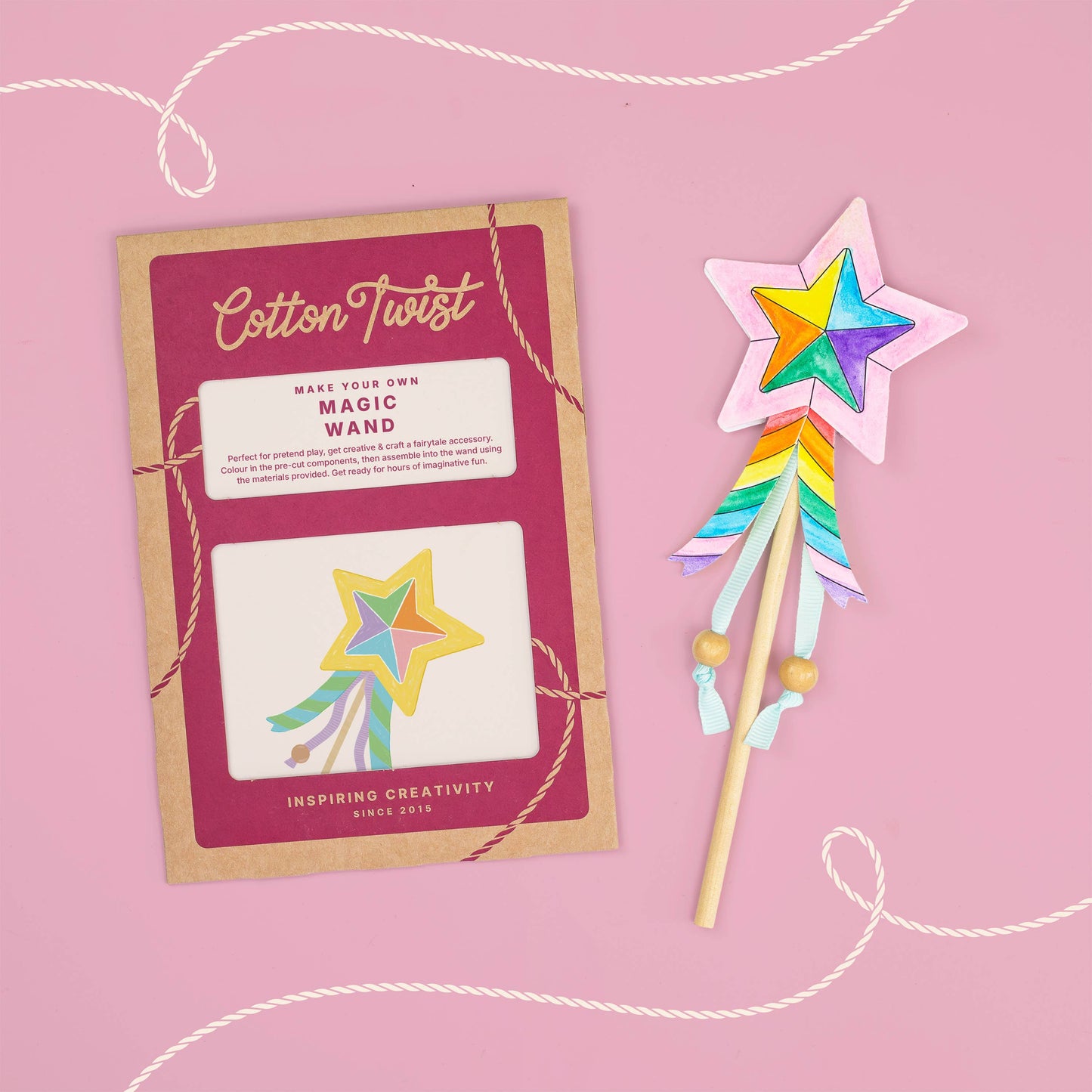 Colorful magic wand with star design next to its packaging on a pink background