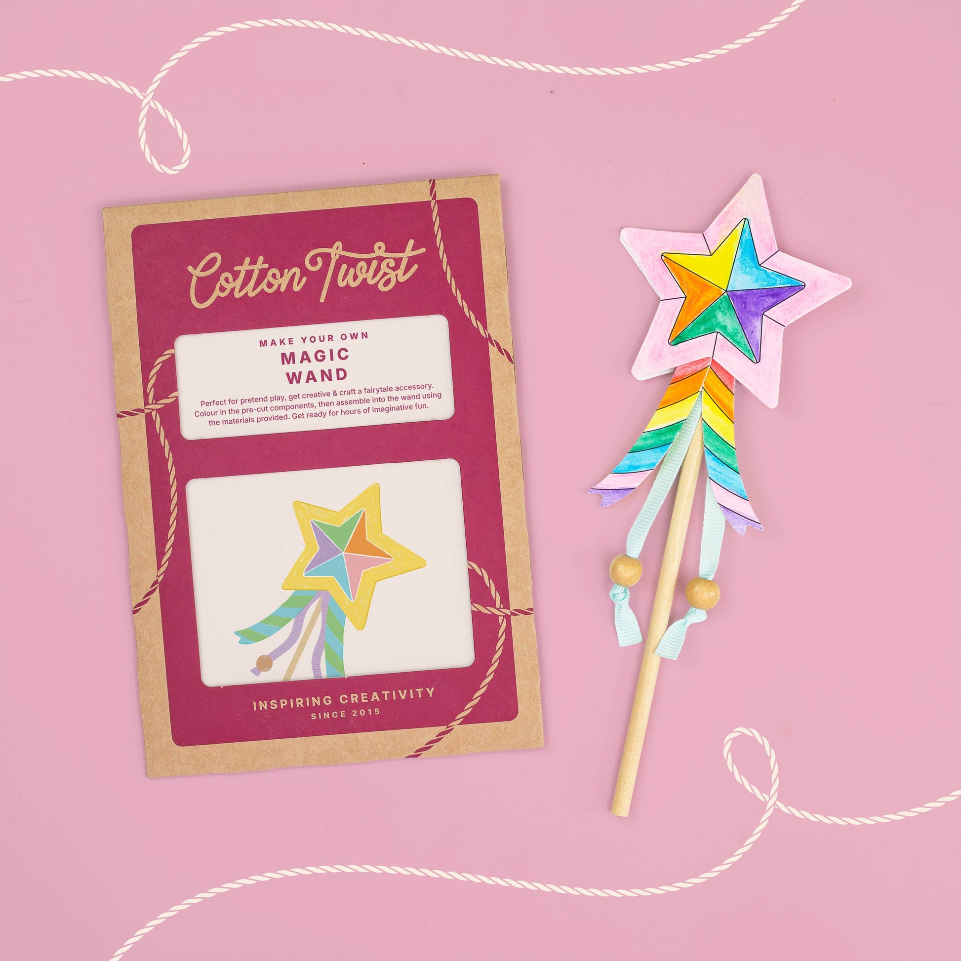 Colorful magic wand with star design next to its packaging on a pink background