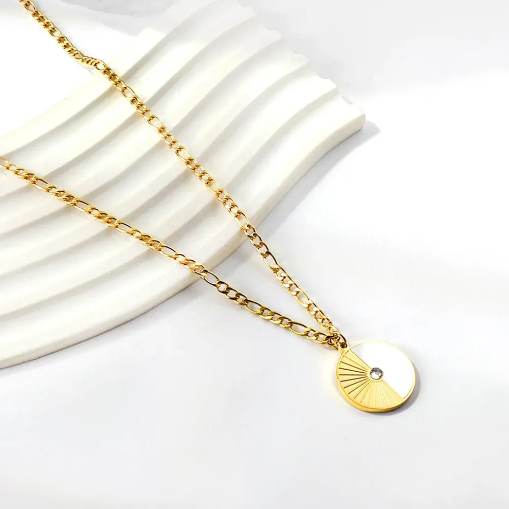 Gold necklace with a circular pendant on a white background