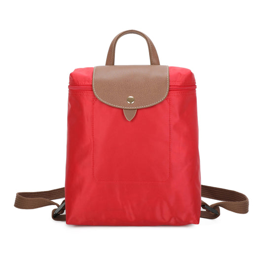 A red nylon backpack with a brown leather flap and top handle, featuring a front pocket and adjustable shoulder straps, shown against a plain white background.