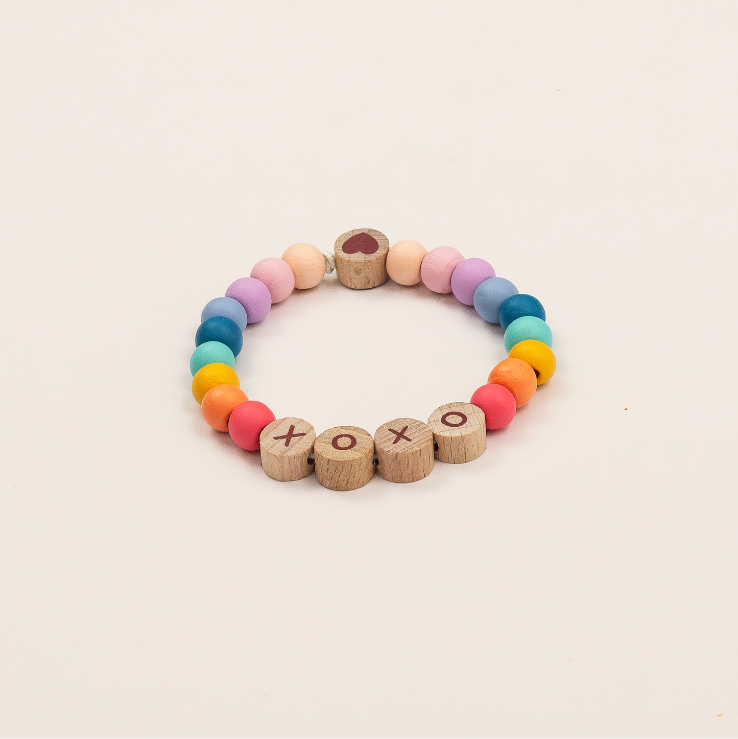Colorful beaded bracelet with wooden letters on a beige background