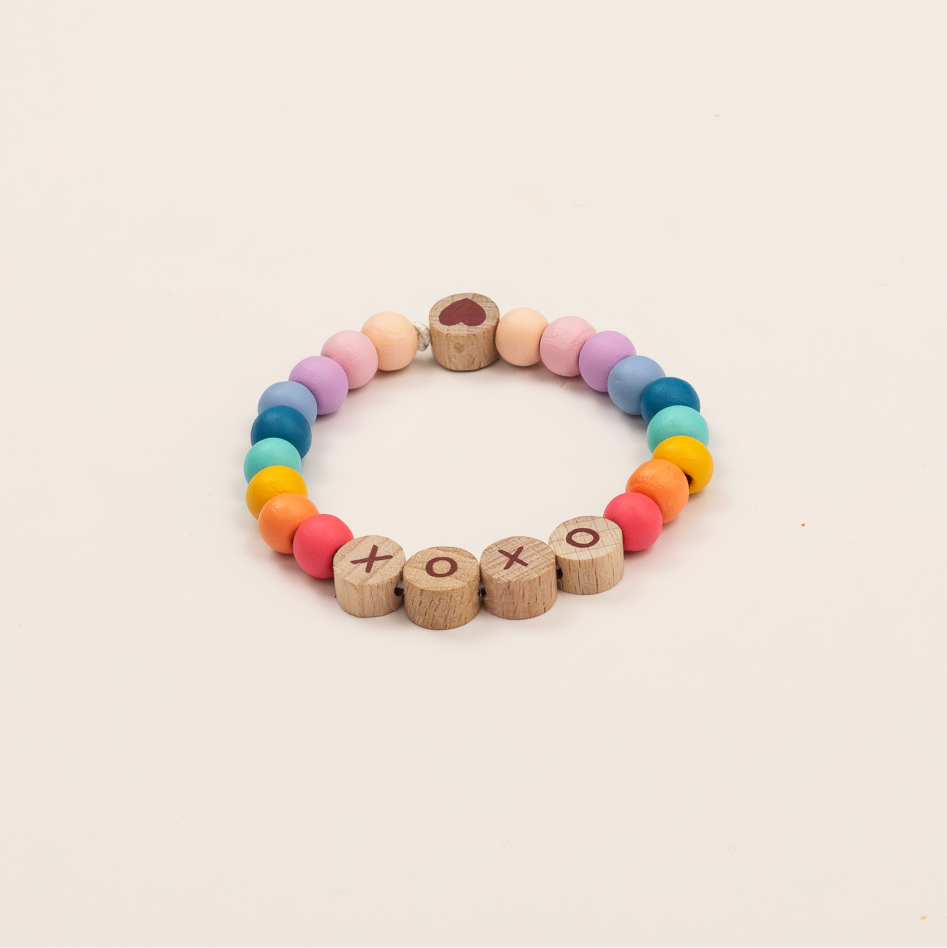 Colorful beaded bracelet with wooden letters on a beige background