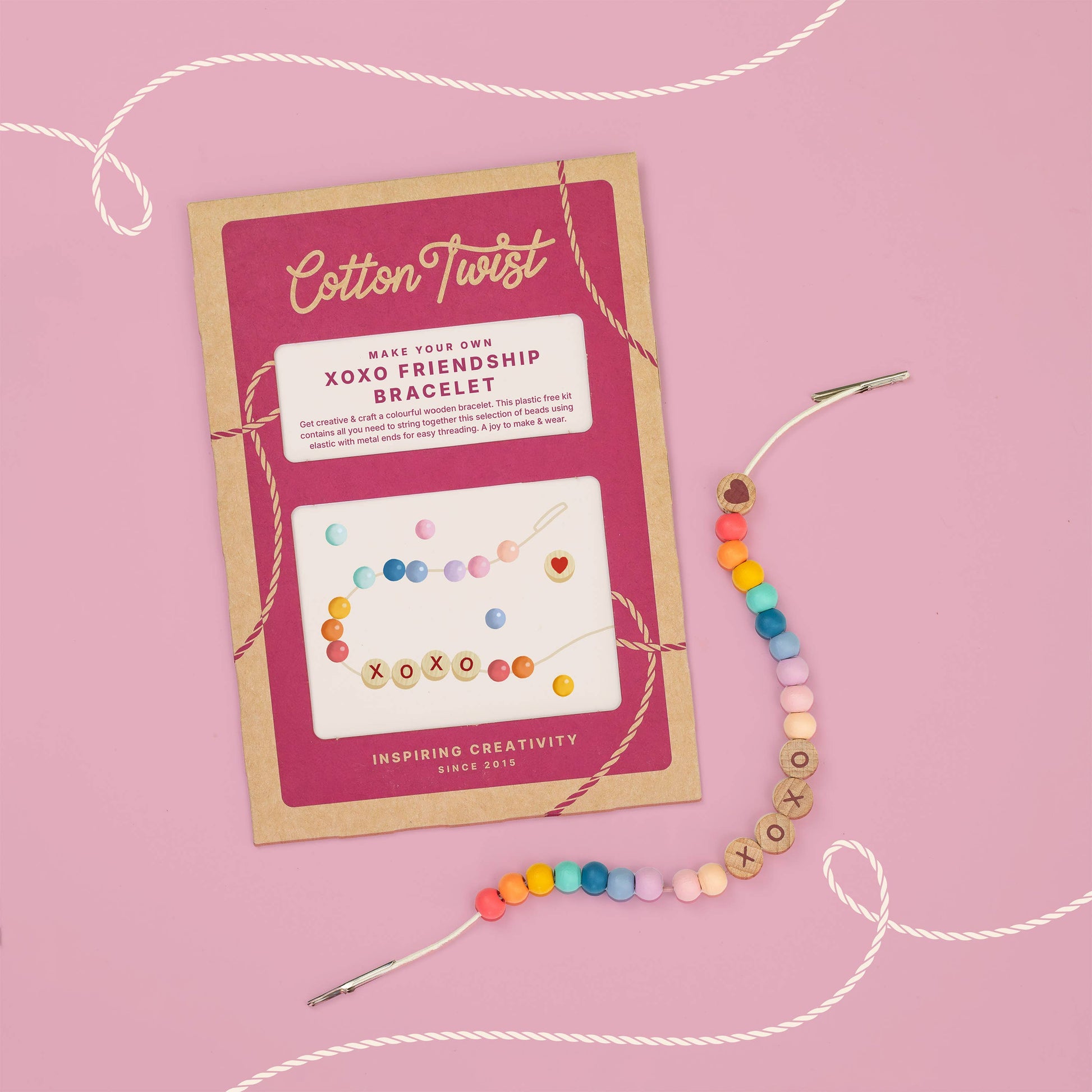 Colorful friendship bracelet with packaging on a pink background