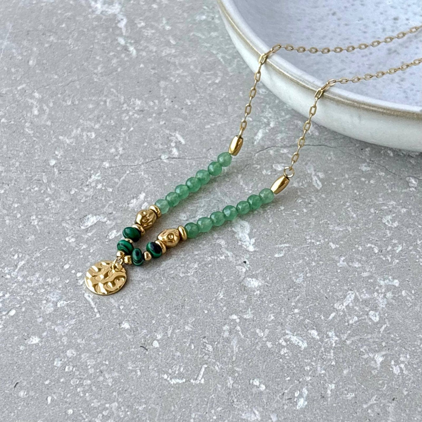 Necklace with green beads and gold accents on a gray surface