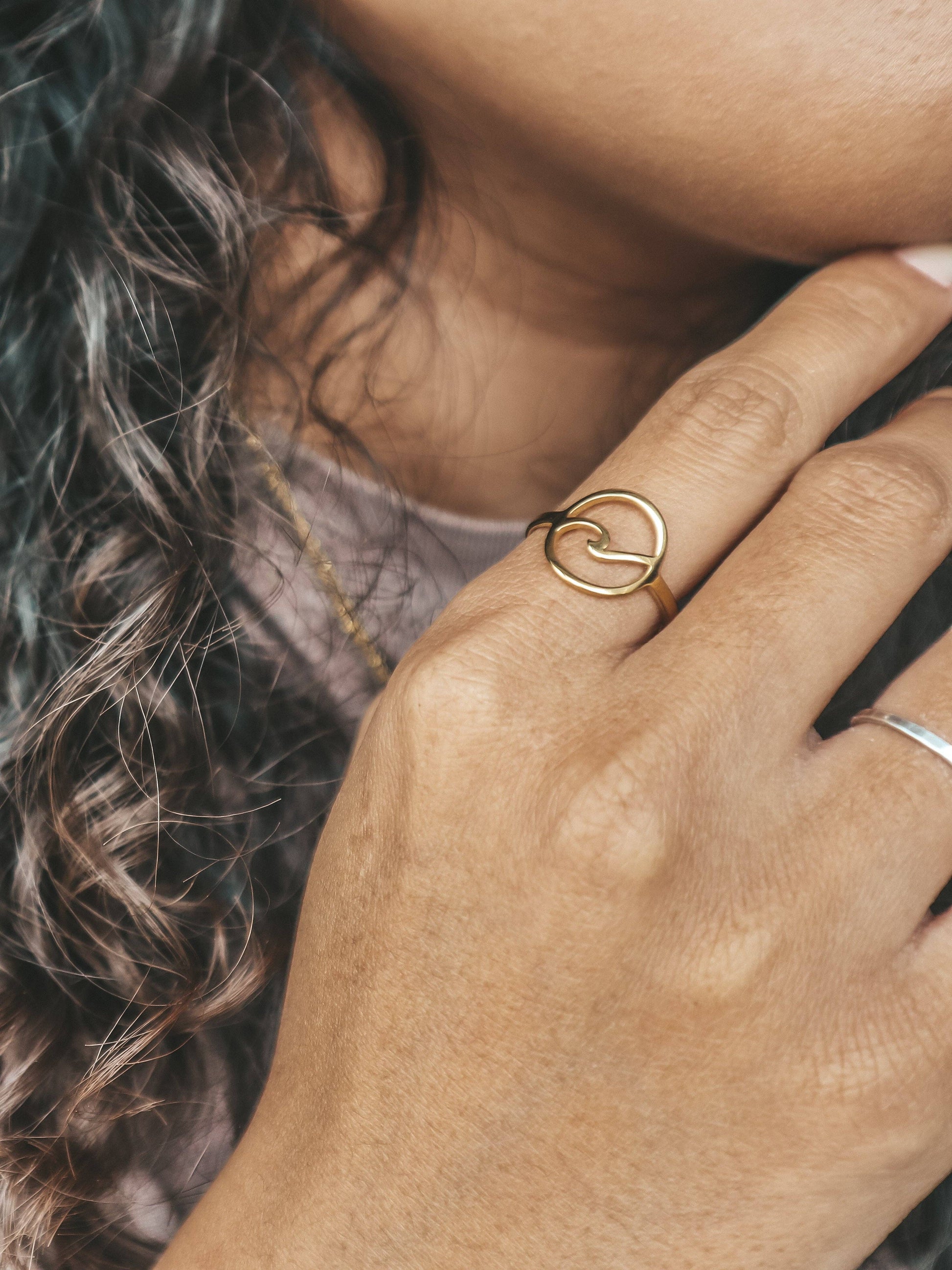 Close-up of a hand wearing a gold ring with a blurred background