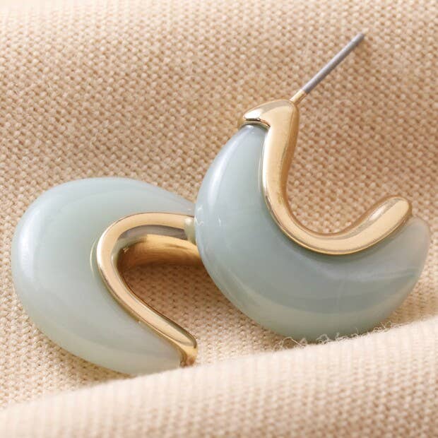 Gold and light blue earrings on a beige fabric background