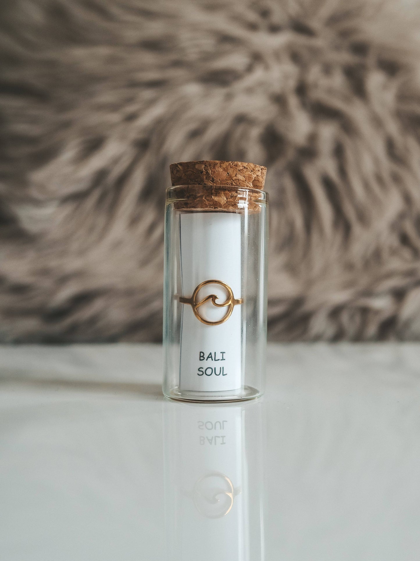 Glass jar with cork lid labeled 'Bali Soul' on a white surface with a textured brown background.