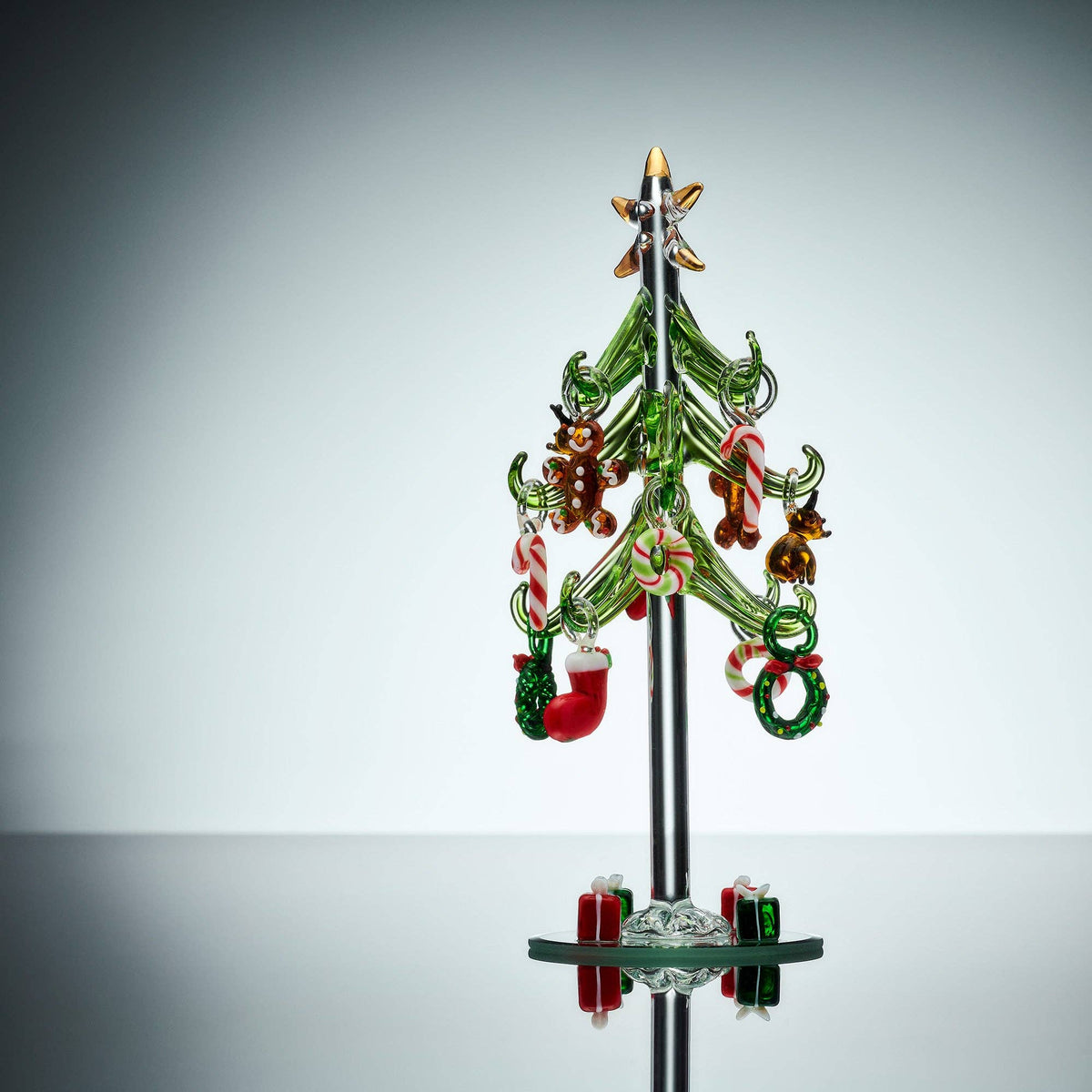 Decorative glass Christmas tree with colorful ornaments on a gray background