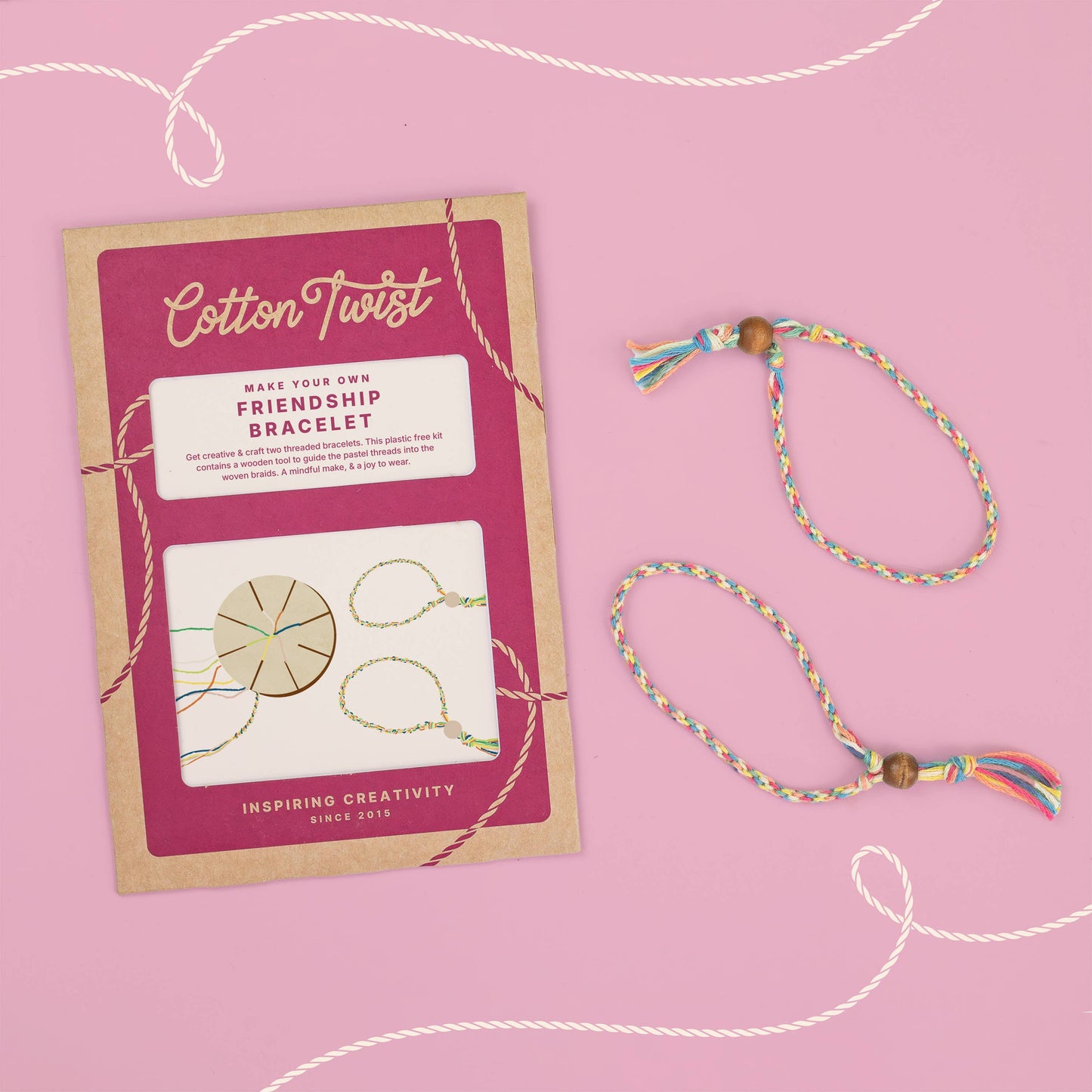 Cotton Twist friendship bracelet kit with a completed bracelet on a pink background