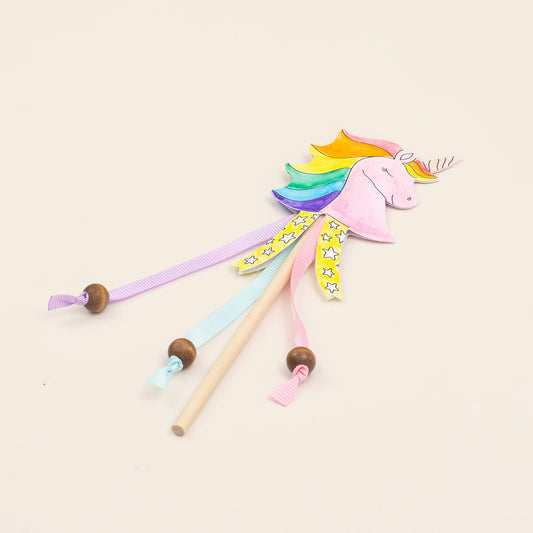 Colorful unicorn toy with wooden sticks on a light beige background